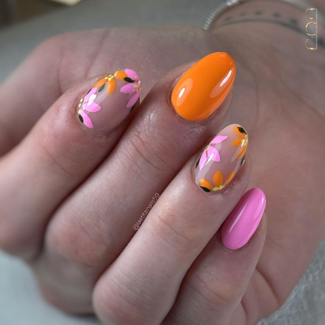 Pose d'ongles amandes rose et orange avec nail art fleurs