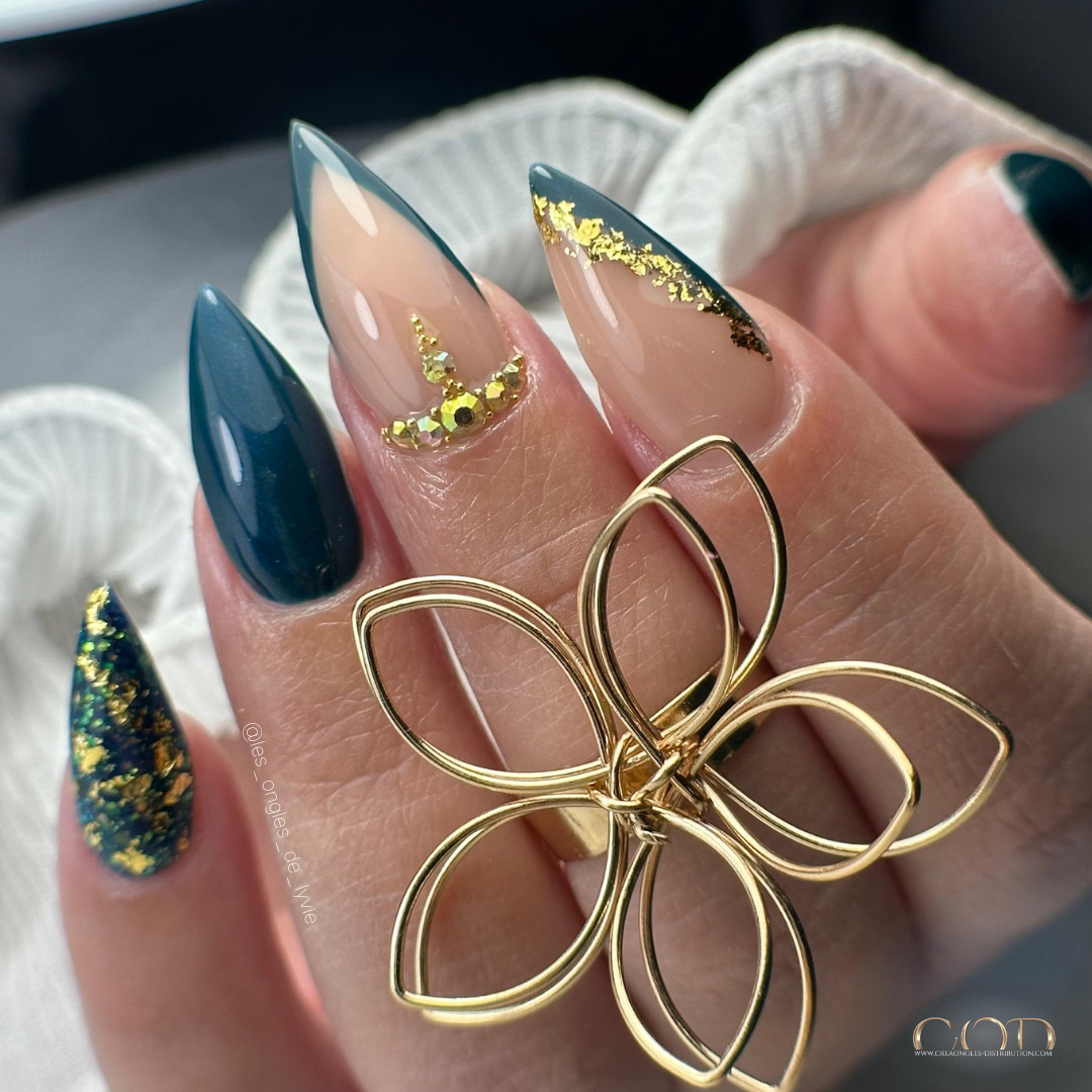 Pose d'ongles stilettos longs bleu pétrole irisée et pailletée avec french, strass et flakes or
