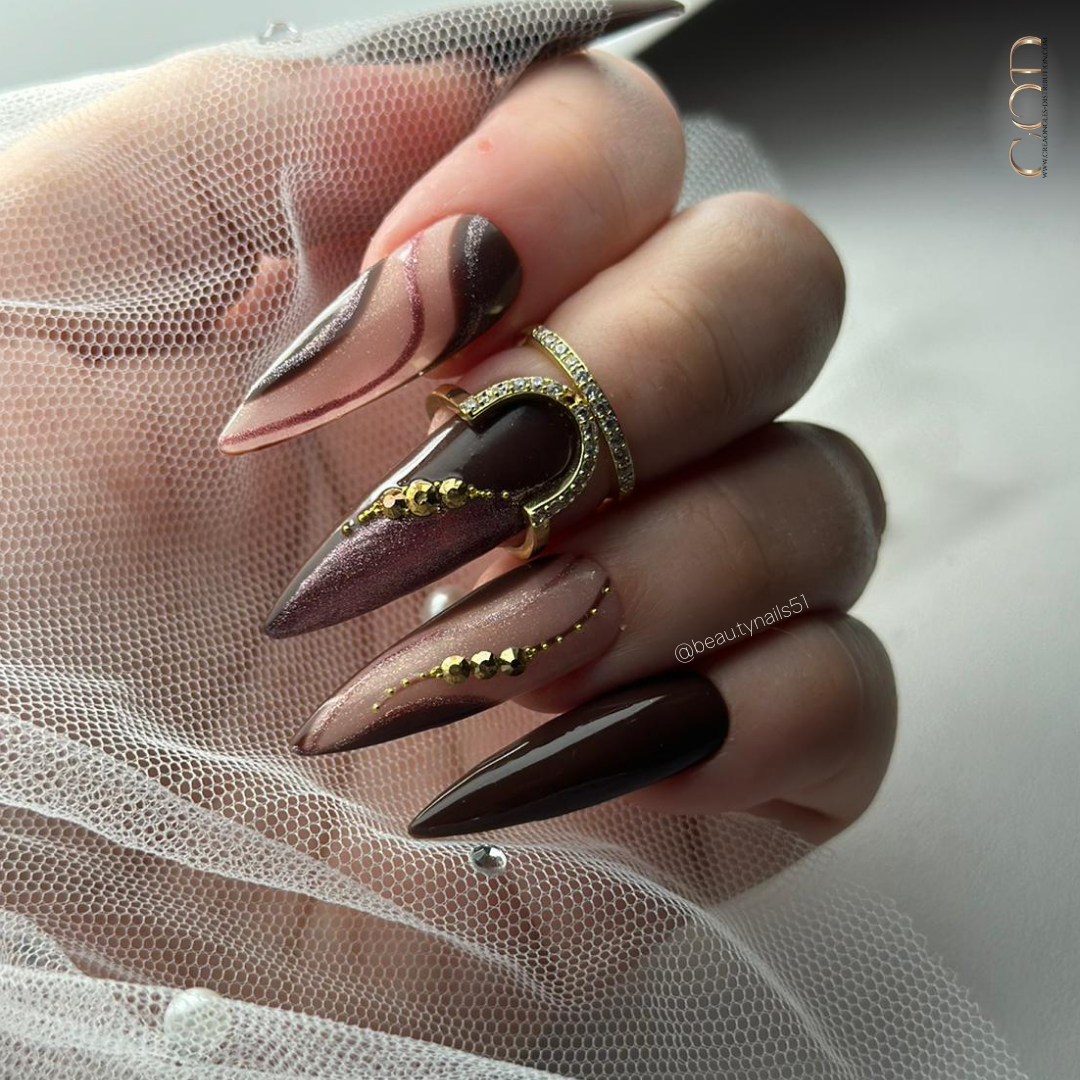 Pose d'ongles stilettos longs marron avec nail art lignes fines et pailleté et strass dorés