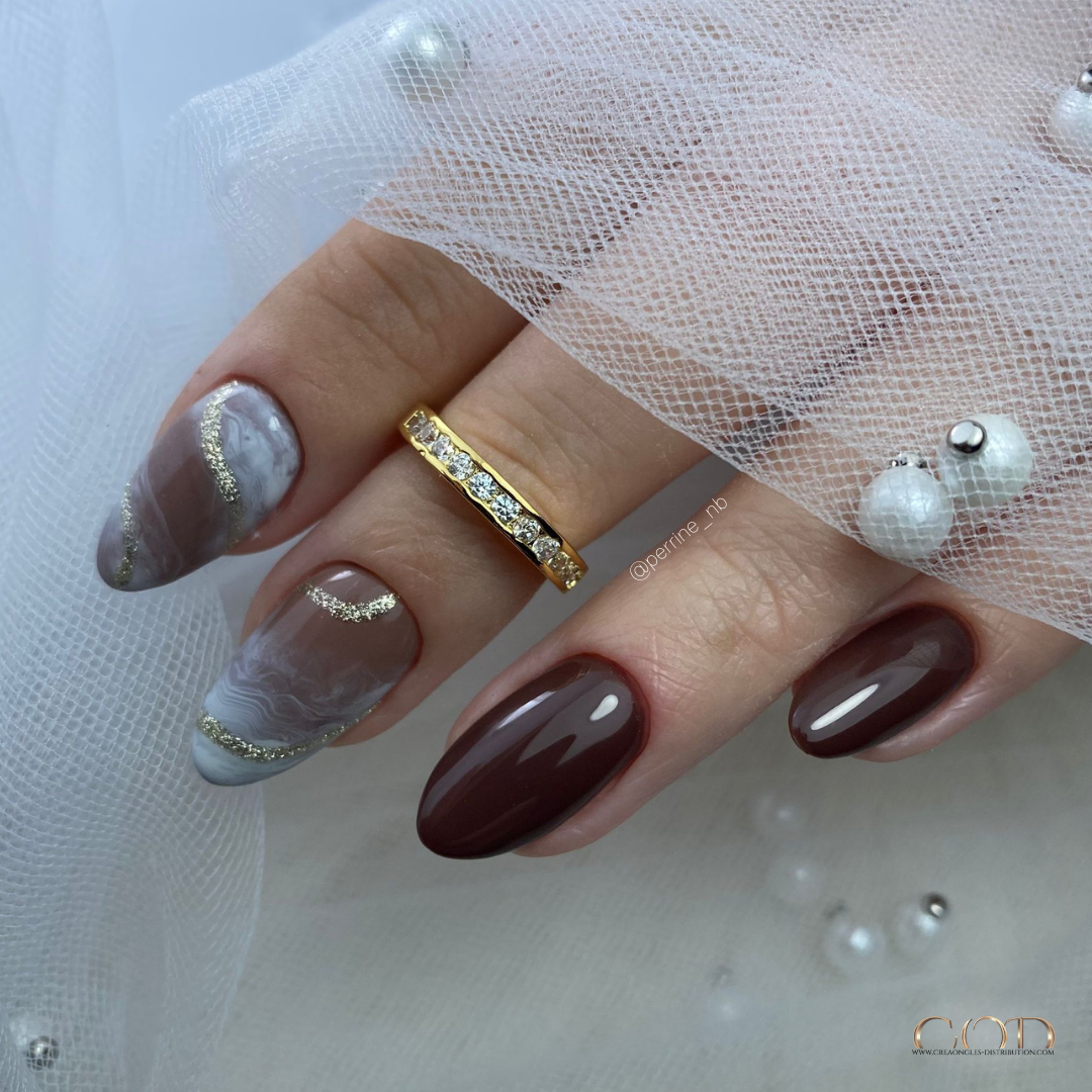 Pose d'ongles en amandes marron avec nail art marbré et doré