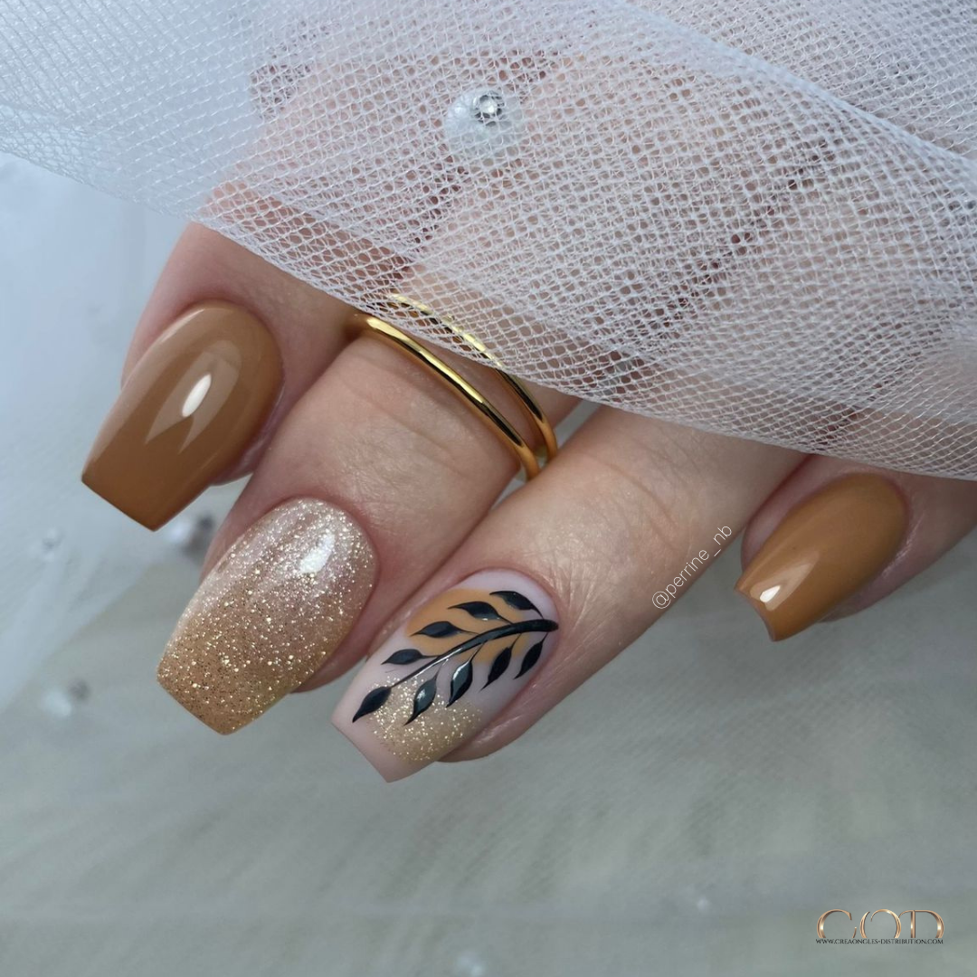 Pose d'ongles coffin courts marron caramel pailletés avec nail art feuillage