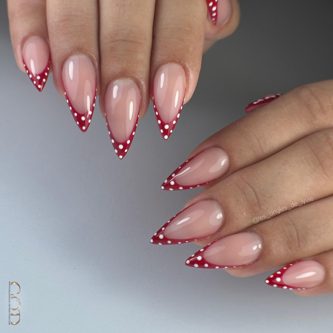 Pose d'ongles stilettos avec french rouge à pois blancs