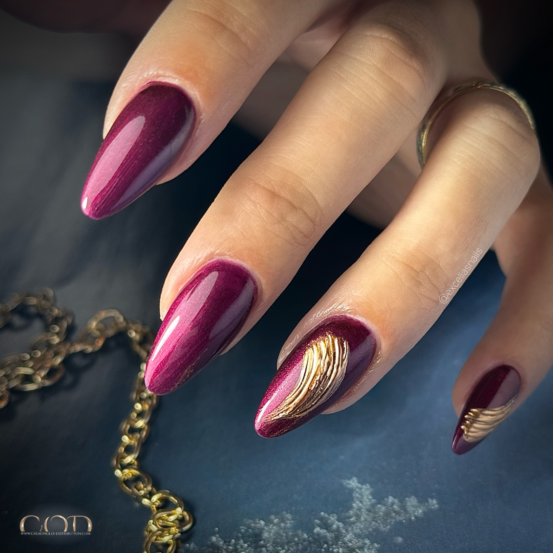 Pose d'ongles en amandes longues bordeaux irisiée avec nail art en relief chromé doré