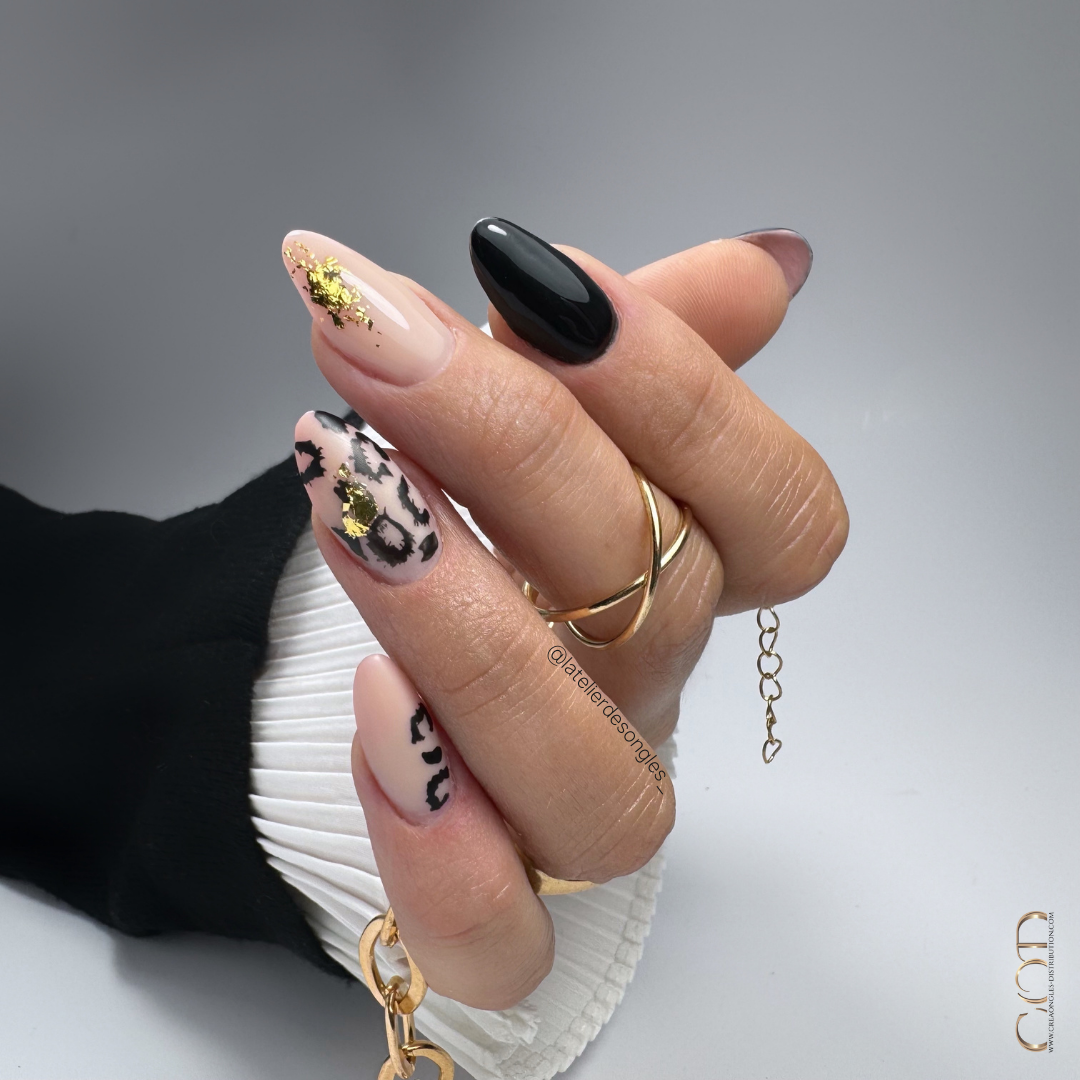 Pose d'ongles en amande nude beige et noir avec nail art léopard et flakes or