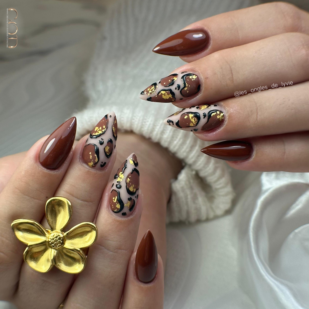 Pose d'ongles stiletto marron avec nail art léopard 3D et flakes or