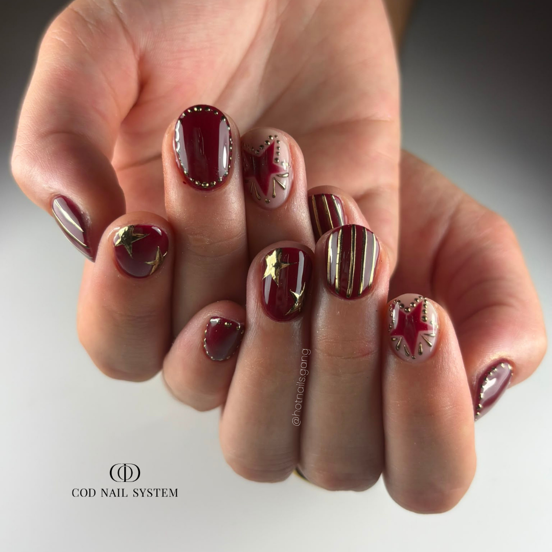 Pose d'ongles courts bordeaux et chrome doré Pose d'ongles en gainage bordeaux avec nail art chrome et étoiles