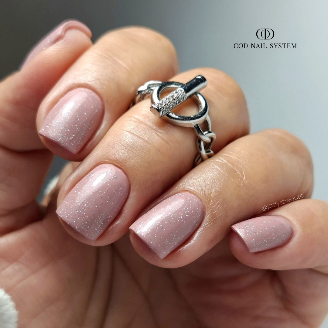 Ongles carrés nude rose pailletés Pose d'ongles carrée nude rosé avec finition pailletée holographique