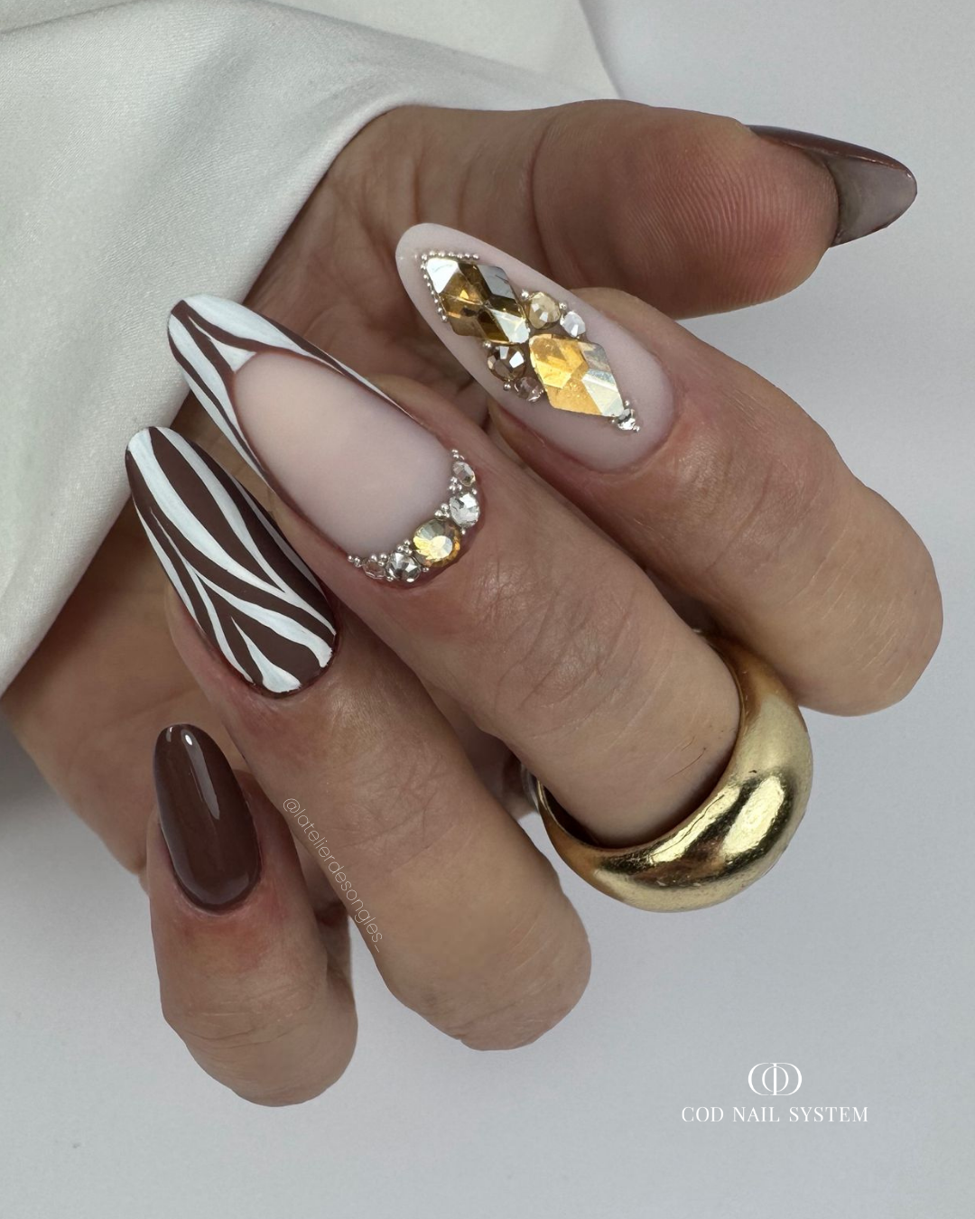 Pose d'ongles en amandes marron, zébré et matt Pose d'ongles en amandes matt marron et blanches avec nail art zébré et bijoux d'ongles