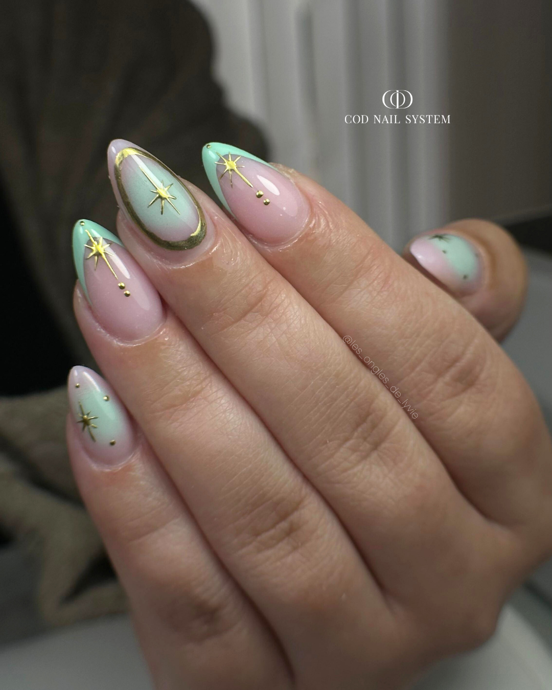 Pose d'ongles en amandes vert pastel avec french et nail art étoiles chrome doré