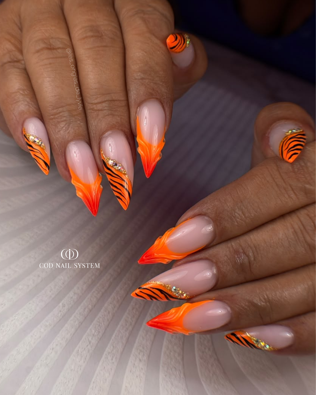 Pose d'ongles stilettos néon orange zébrés 3D Pose d'ongles stilettos néon orange avec nail art zébré et 3D