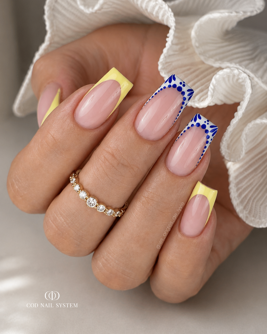 Pose d'ongles carrée avec french jaune pastel et nail art céramique bleu et blanc