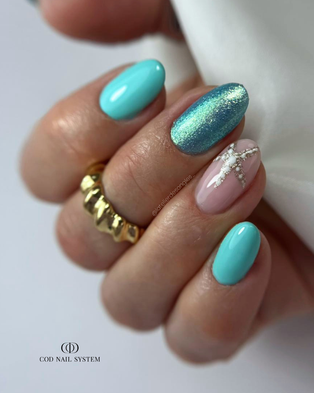 Pose d'ongles en amandes bleu turquoise et pailletée avec nail art étoile de mer dorée
