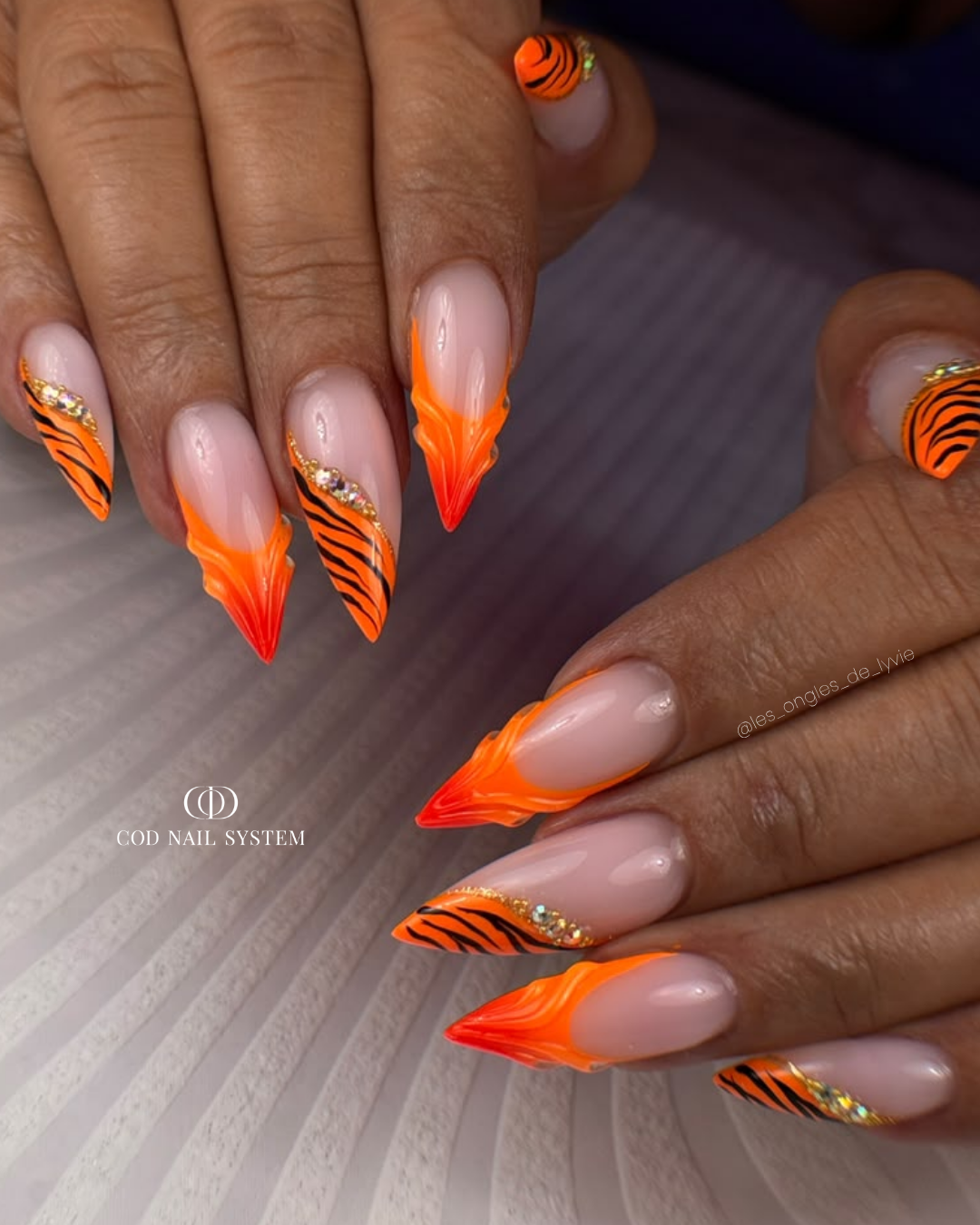 Pose d'ongles en stilettos néon orange avec french, nail art tigré et 3D