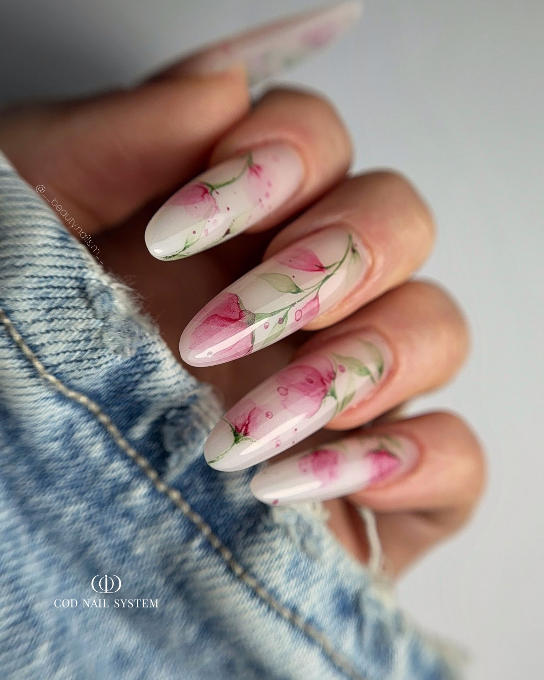 Pose d'ongles en amandes milky white rosé avec nail art fleurs en aquarelle