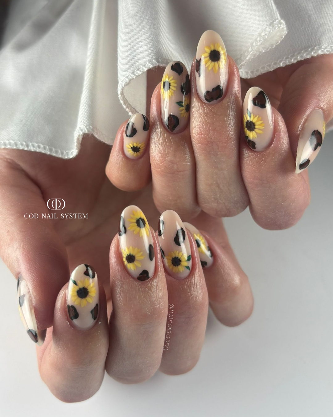 Pose d'ongles en amandes nude beige avec nail art léopard et tournesol