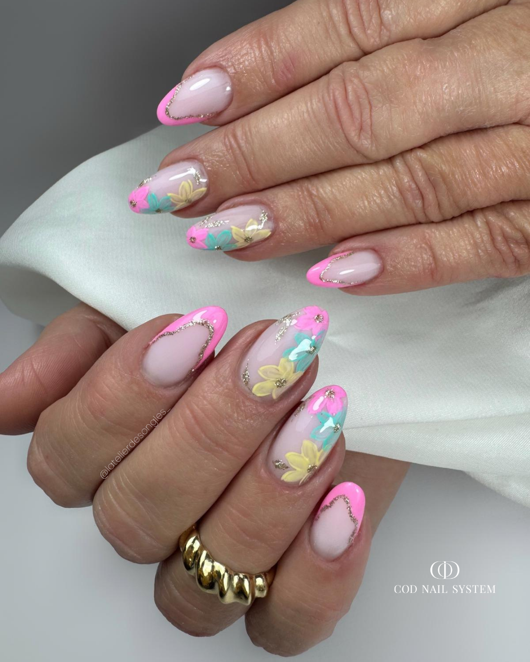 Pose d'ongles en amandes rose, jaune et bleu pastel néon avec french et nail art fleurs