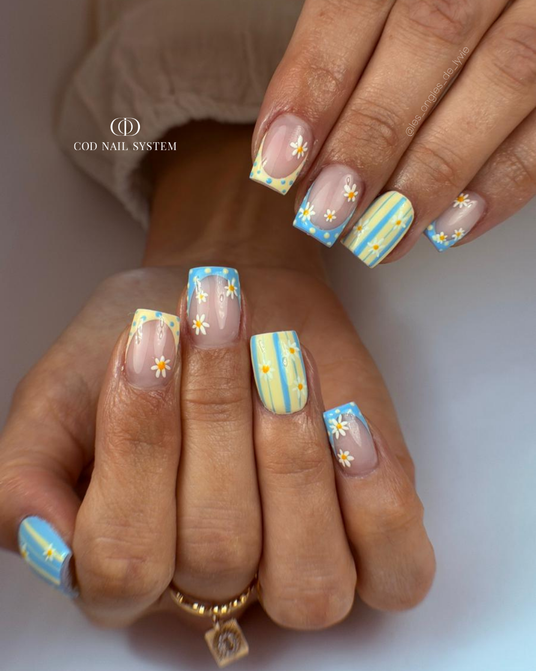Pose d'ongles carrés courts jaune et bleu pastel avec nail art french et petites marguerites