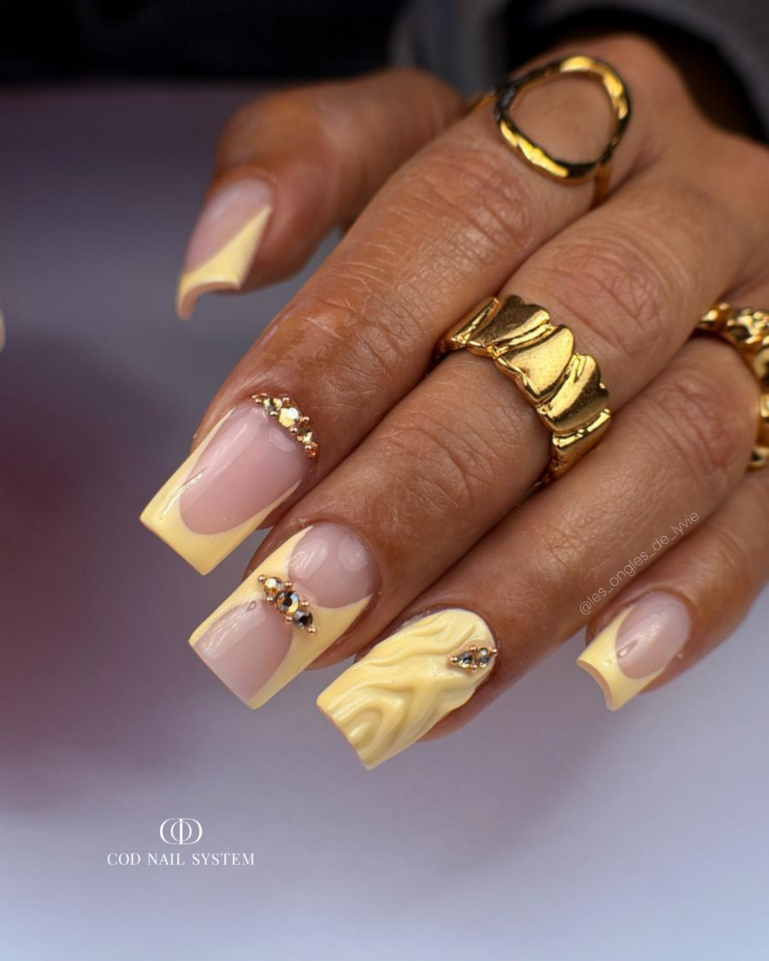 Pose d'ongles carrés jaune pastel avec nail art french, 3D et strass