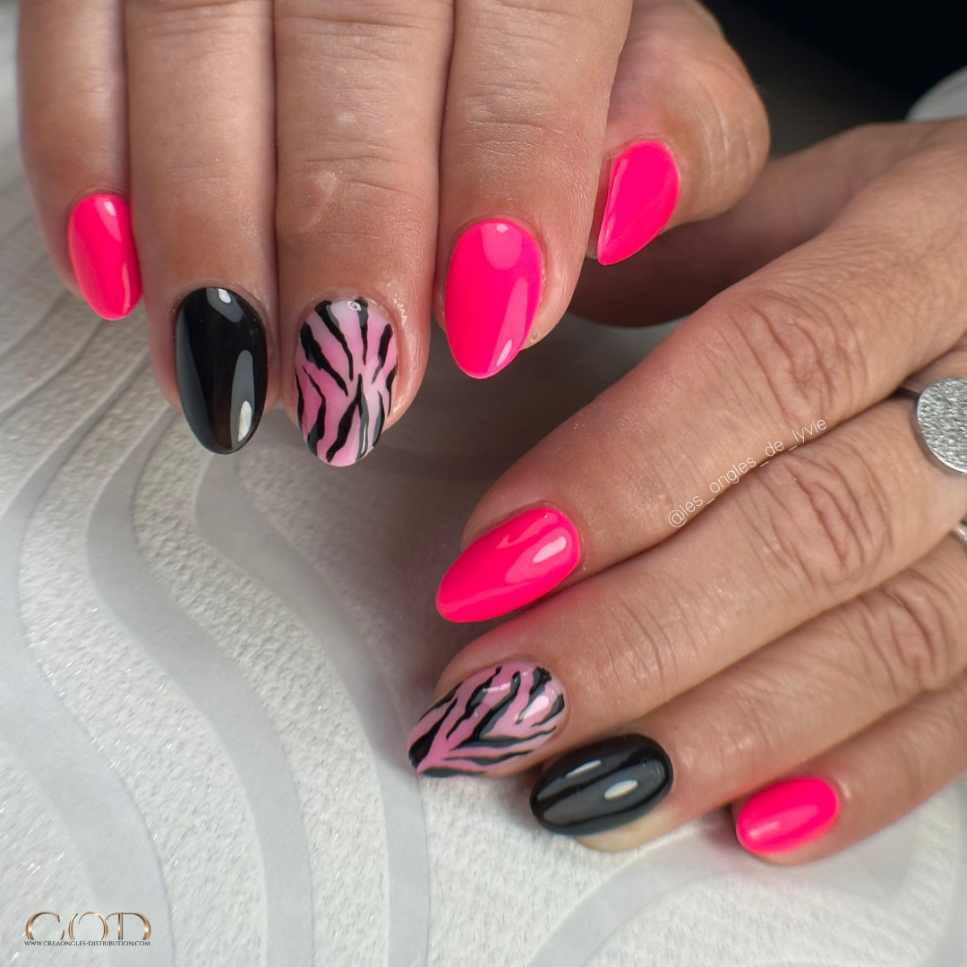 Pose d'ongles en amandes néon rose et noirs avec nail art zébré