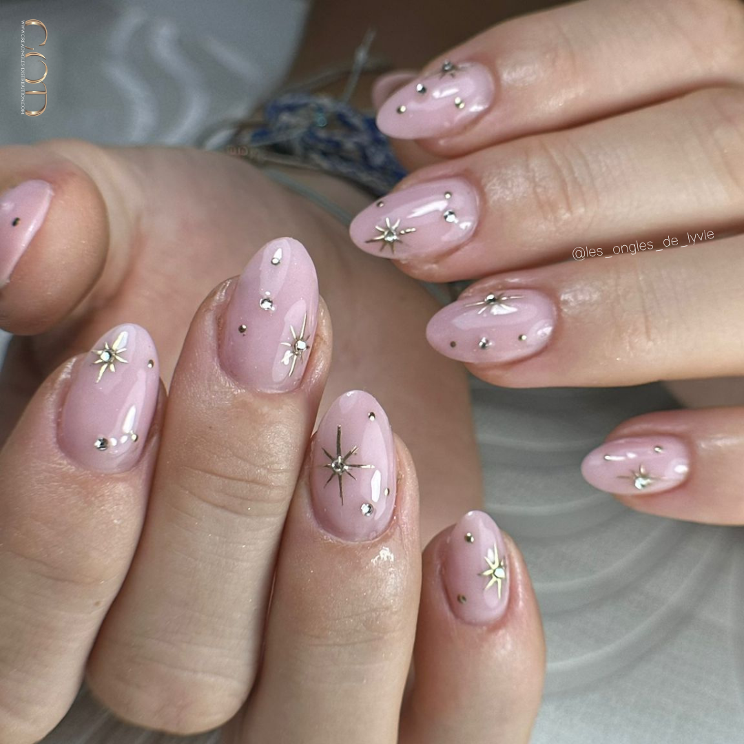 Pose d'ongles en amandes nude rose avec nail art étoiles chrome