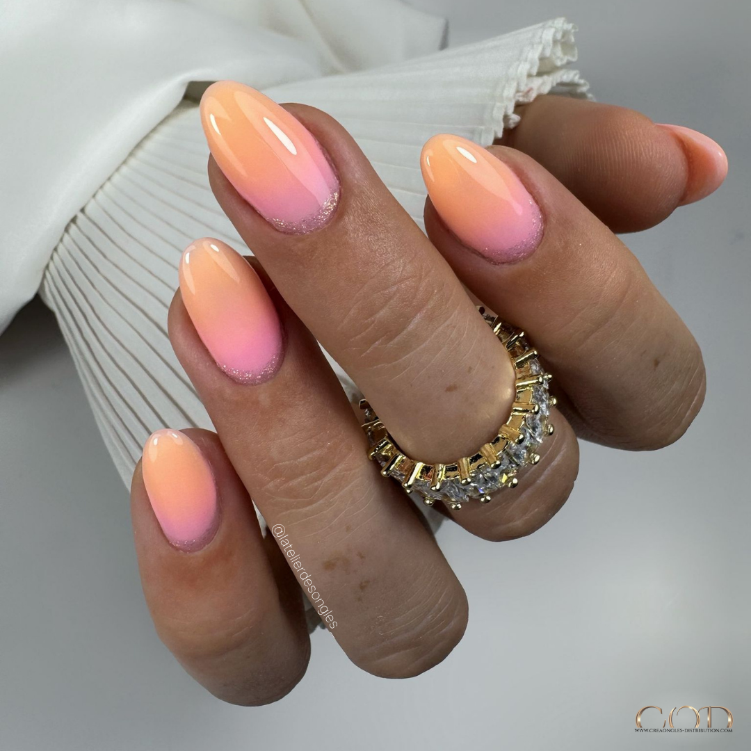 Pose d'ongles en amandes avec dégradés en construction orange et rose et cutiglitter