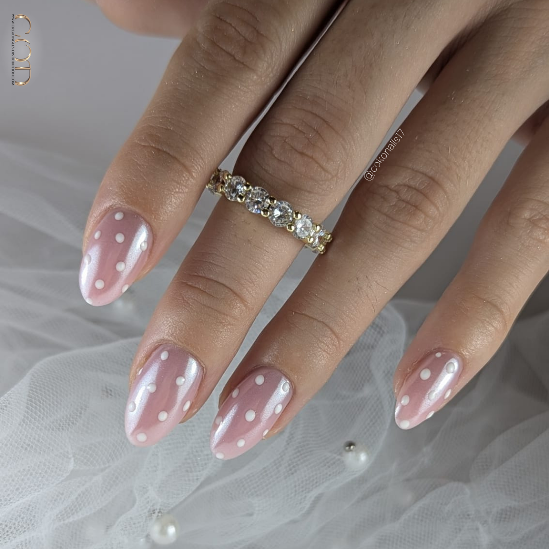 Pose d'ongles en amandes rosés perlés avec nail art pois blancs