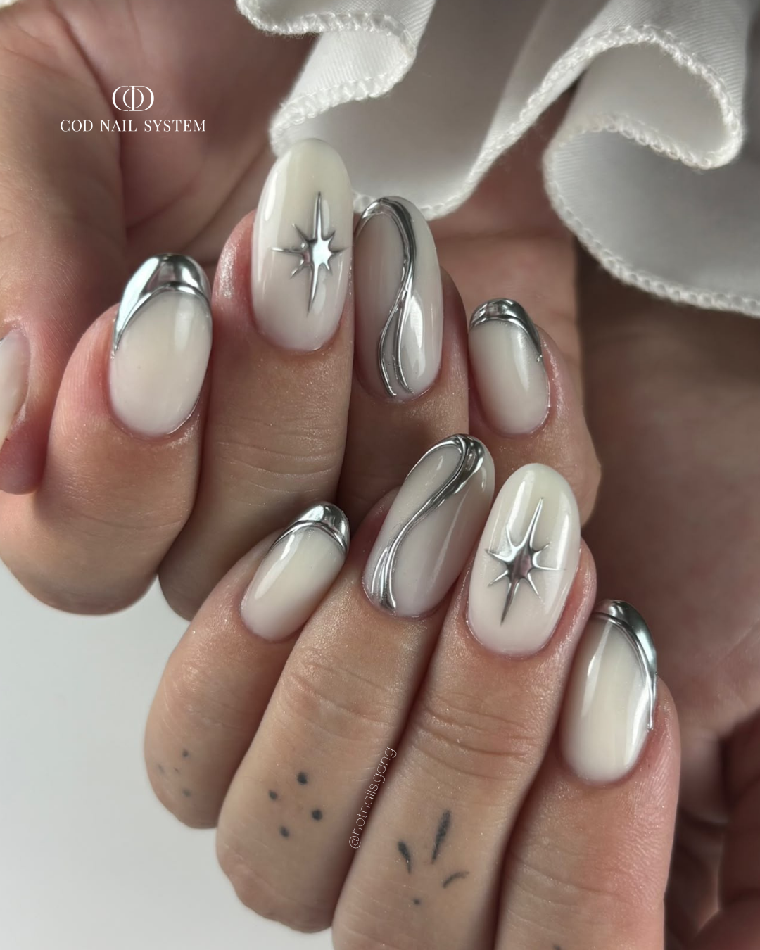Pose d'ongles ovales milky white et chrome silver Pose d'ongles ovales milky white avec nail art en relief chrome argenté