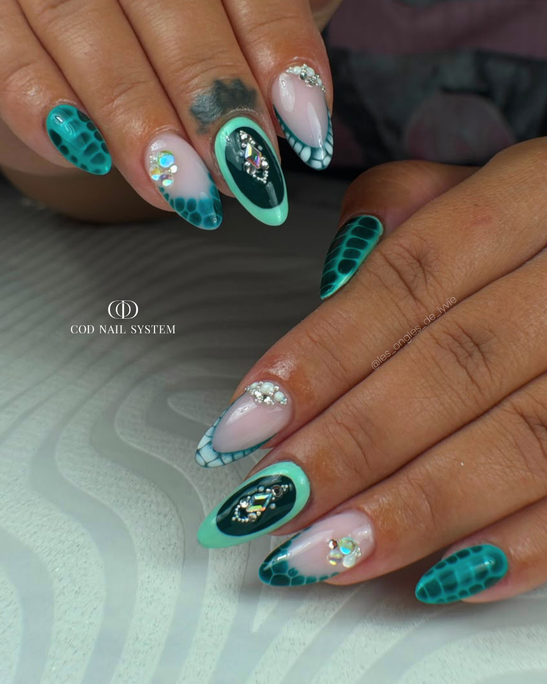 Pose d'ongles amandes nail art blooming et strass Pose d'ongles amandes bleu et vert avec nail art blooming, french et bijoux en strass