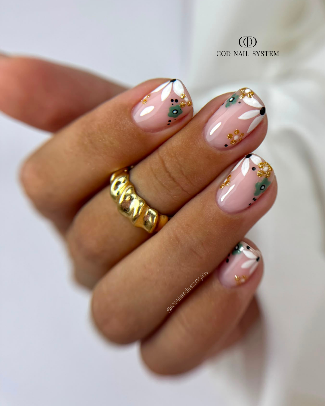 Pose d'ongles carrés arrondies avec nail art fleurs Pose d'ongles carrés arrondis avec nail art fleurs kaki, doré et blanches